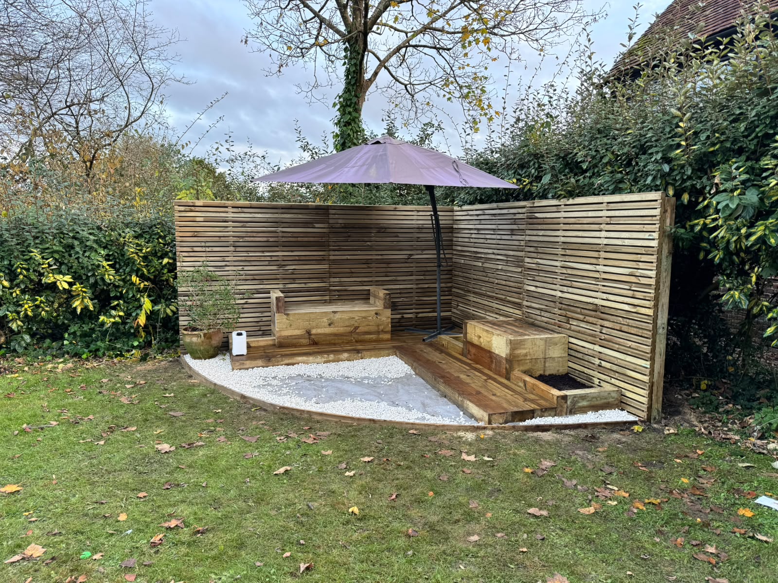 Curved slatted screen with built-in seating framing a garden corner