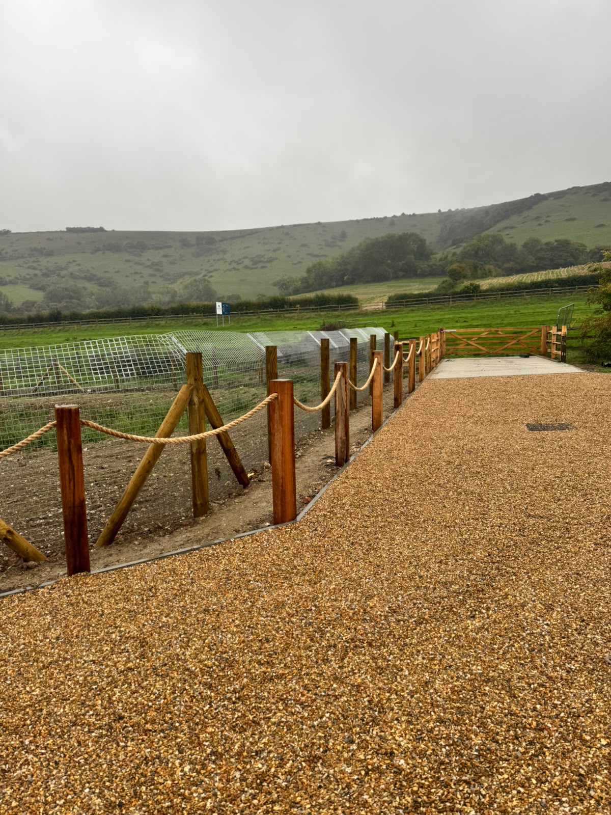 Rope-and-post edging beside a mesh run leading to a field gate