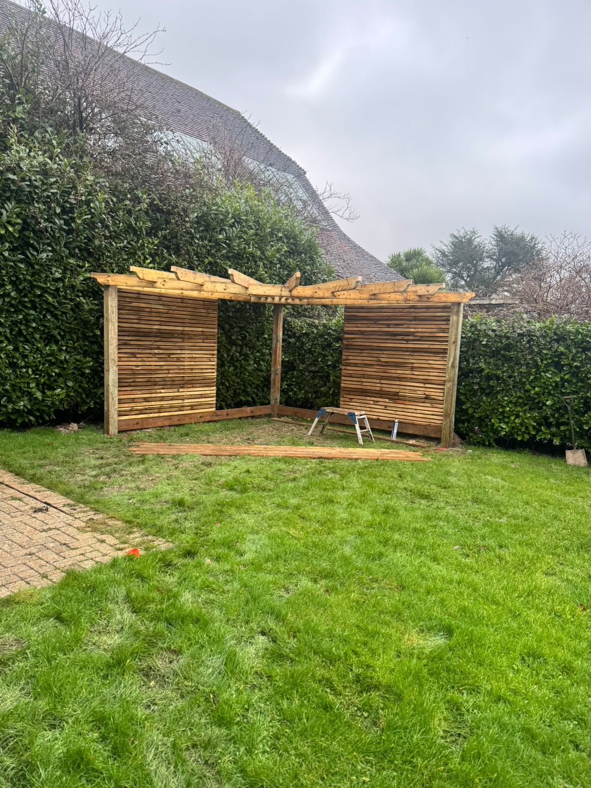 Slatted pergola screens under construction in a country garden
