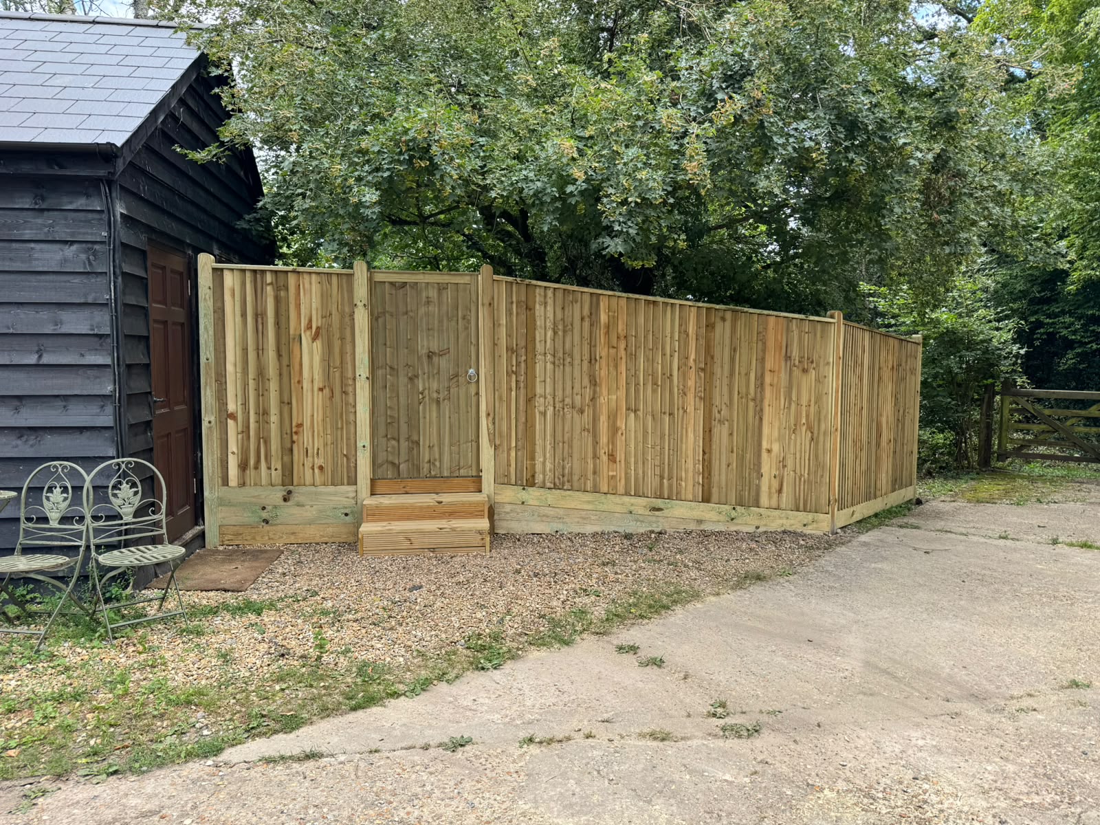 Feather-edge fencing and gate around a cabin on a gravel base