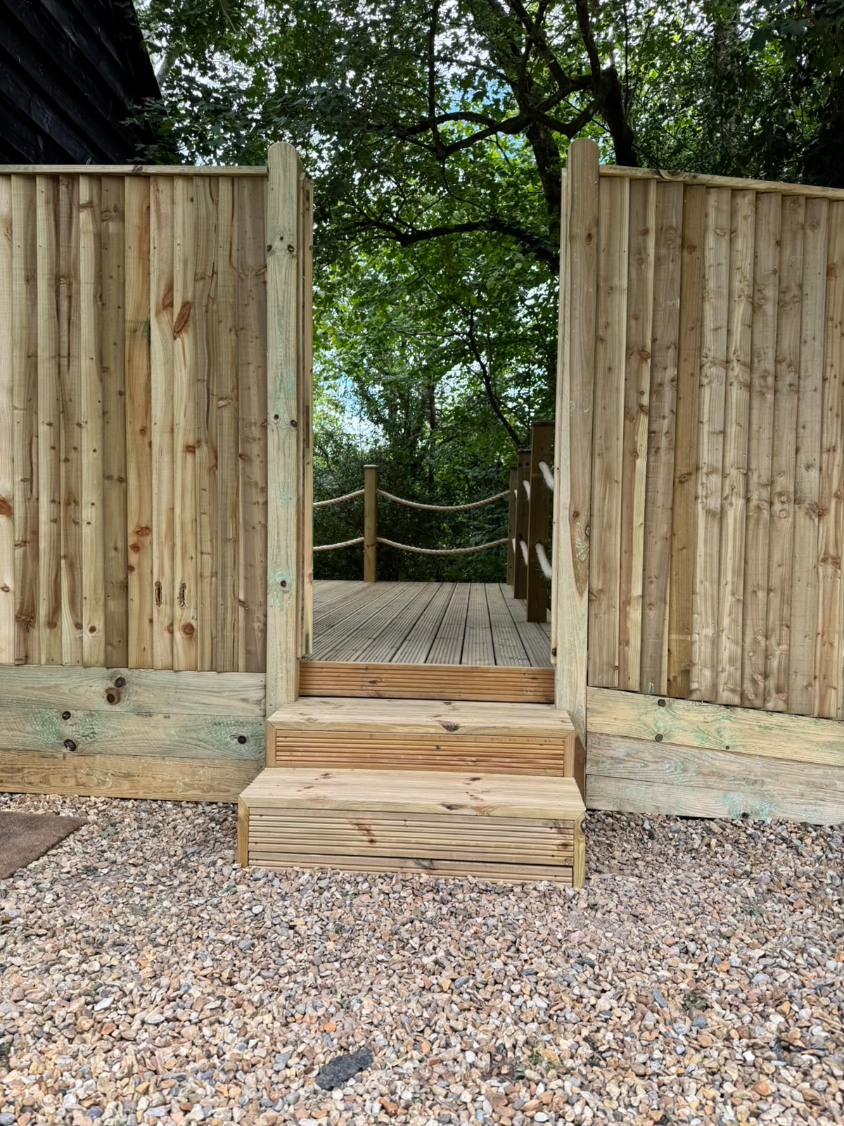 Timber steps leading up to a deck flanked by picket fencing