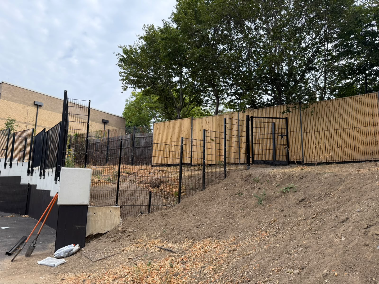Black welded mesh above timber slat infill on a sloped bank