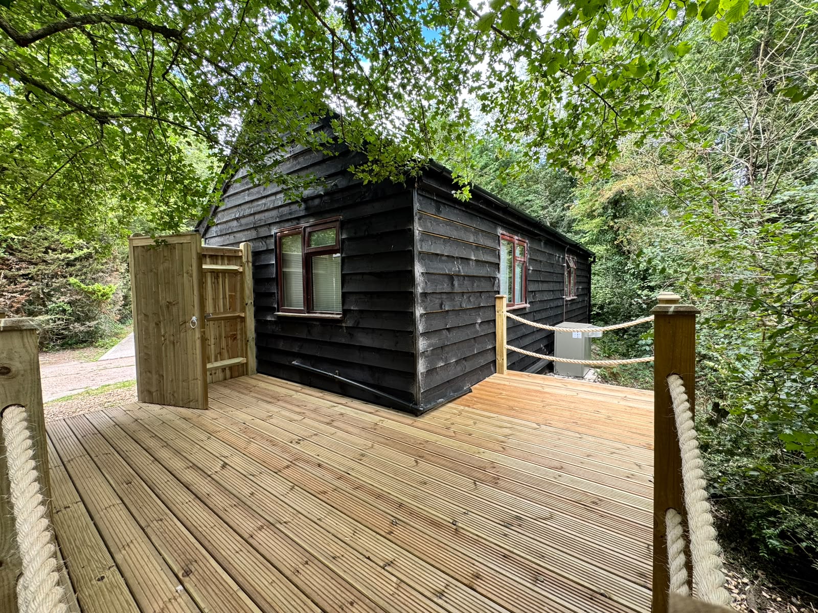 Timber decking surrounding a log cabin with rope balustrades