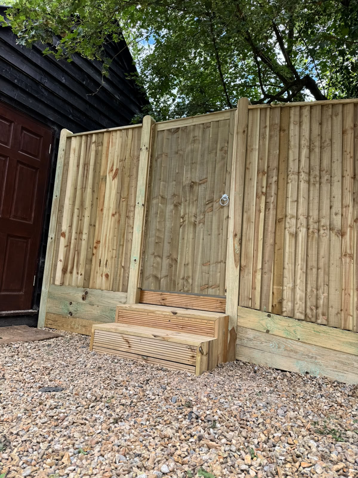 Feather-edge fencing and gate with matching timber steps at a cabin entrance