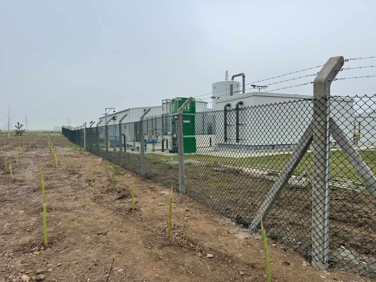 Chain-link compound around utility buildings topped with barbed wire