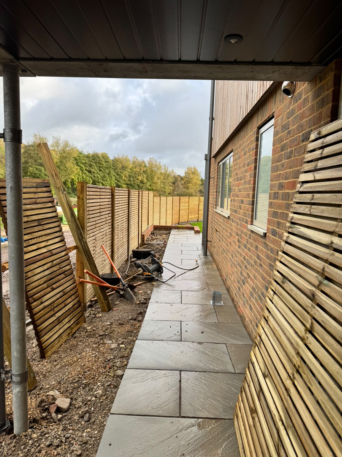Paved side path edged with slat fencing and planting