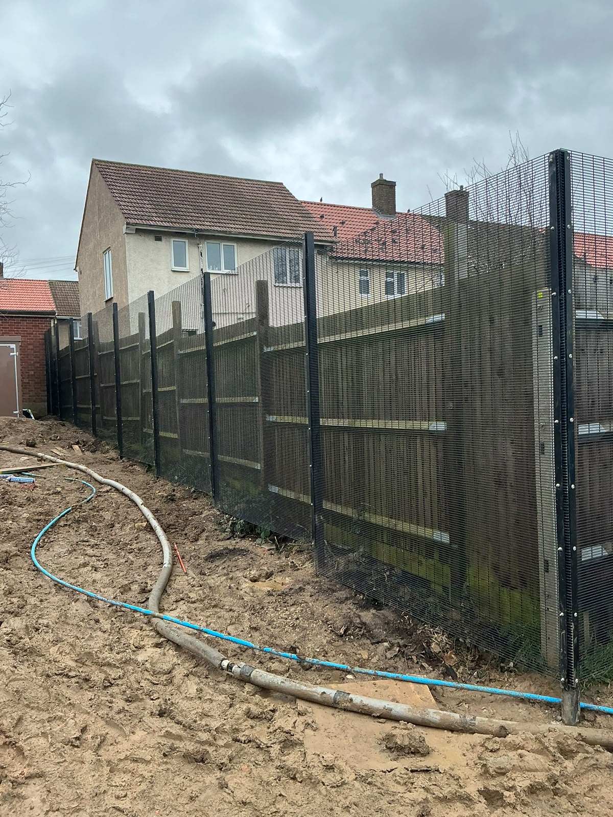 Black high-security mesh panels on stout posts beside homes