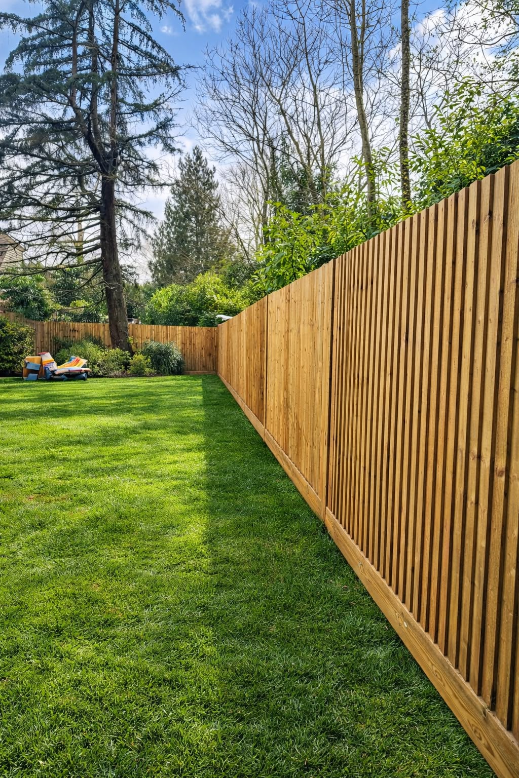 Tall vertical slat fencing enclosing a family lawn