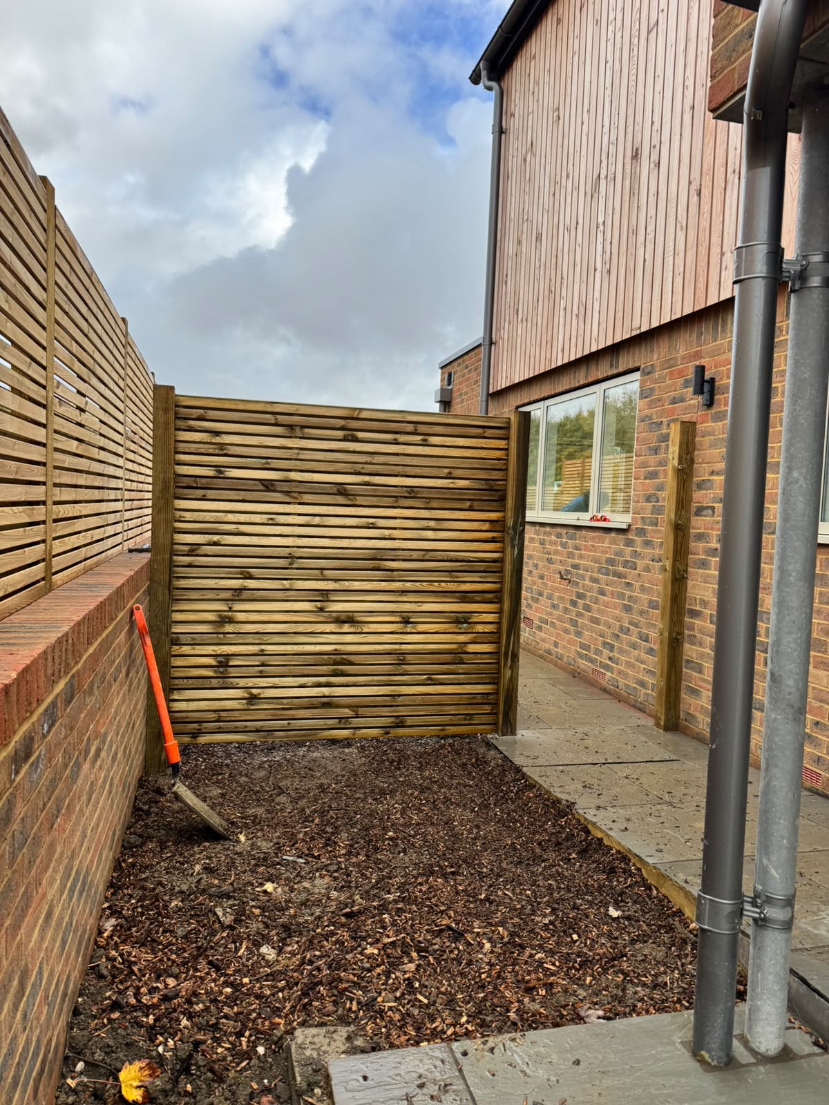 Slatted screening with a matching gate above a planted border