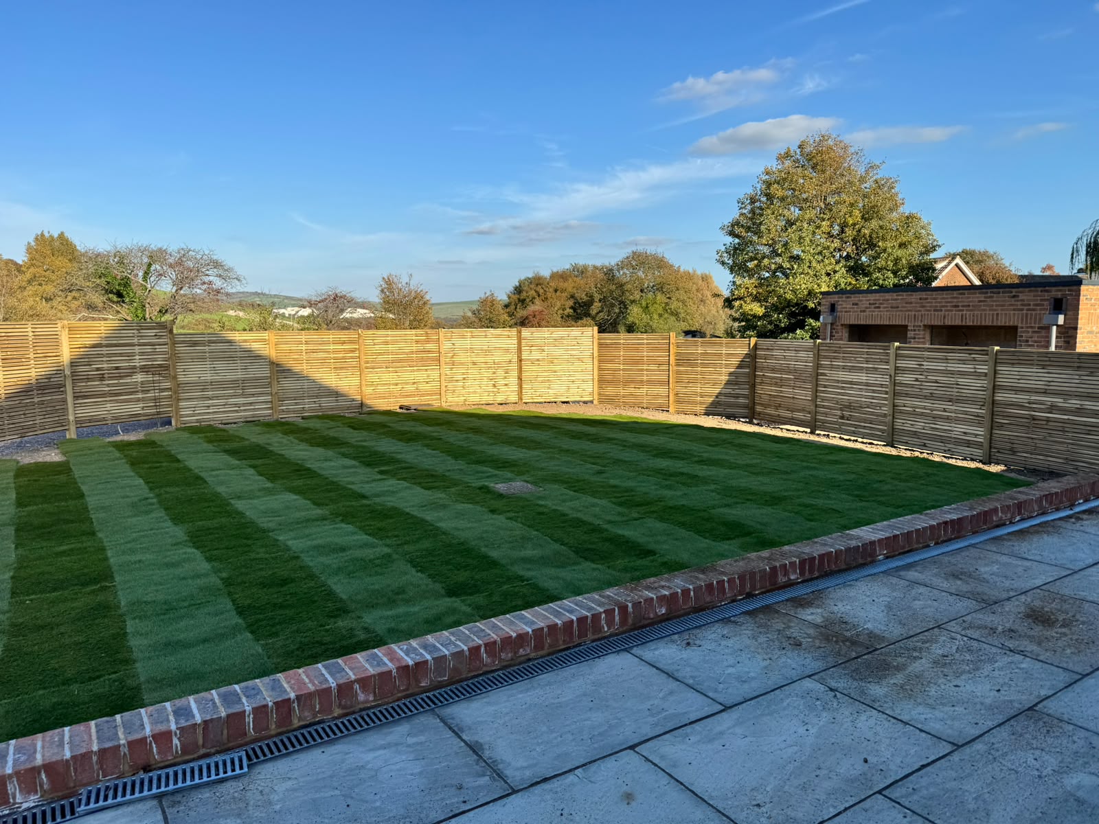 Slatted fencing enclosing a freshly striped lawn and patio