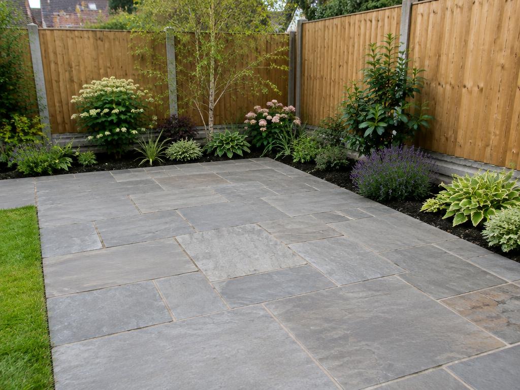 Grey stone paving patio beside planted borders